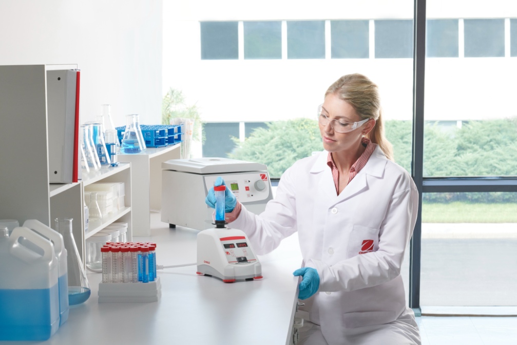 Scientist vortexing a sample on an Ohaus vortex mixer in a laboratory